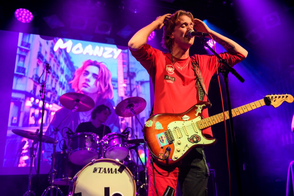 Moanzy performing in red, with his name projected behind him
