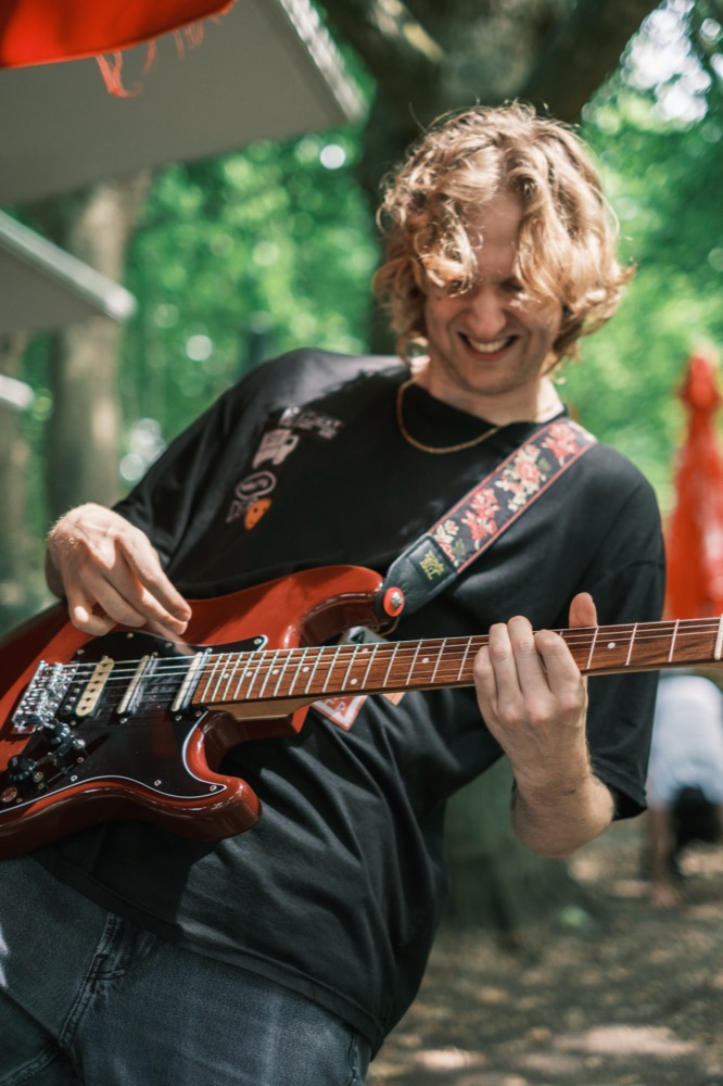 Moanzy playing guitar outdoors, laughing